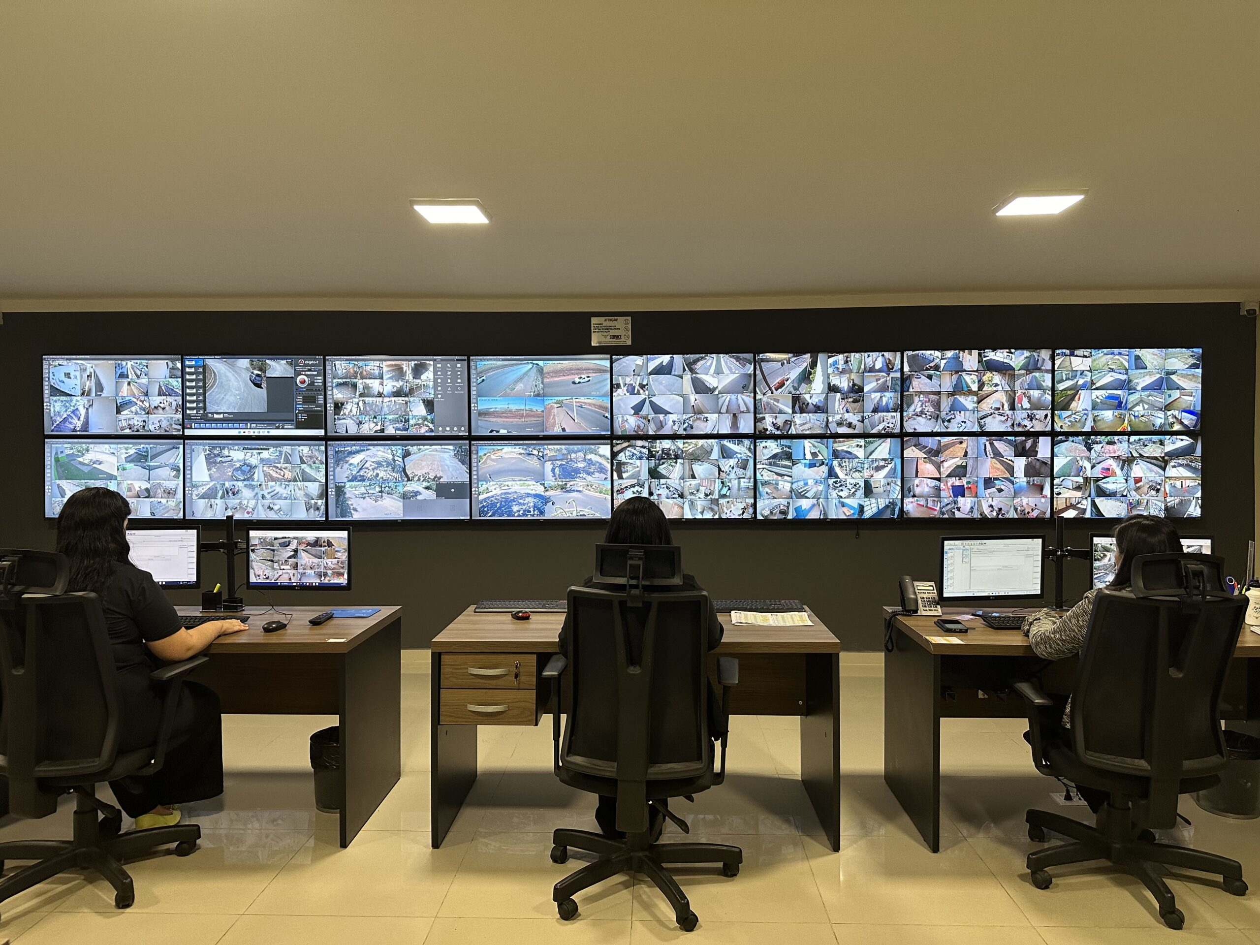 Sala de controle de monitoramento com múltiplas telas e operadores